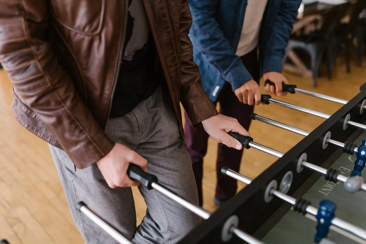 Hands on the handles of a foosball table during a game